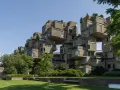 Ein beeindruckendes Beispiel brutalistischer Architektur: Betonblöcke stapeln sich zu einer futuristischen Wohnanlage, umgeben von Grün.