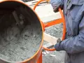 Eine Betonmischmaschine rührt den feuchten Mörtel, der zeigt, aus was Beton besteht: Zement, Wasser und Zuschlagstoffe.