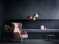 Ein rosafarbener Sessel vor einer anthrazitfarbenen Wand. Die Frage, welche Farbe passt zu Anthrazit, wird hier elegant beantwortet: Zarte Pastelltöne wie dieses Rosa schaffen einen stilvollen Kontrast.