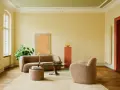 Ein Wohnzimmer mit gelben Wänden und einer grünen Decke, die frisch gestrichen wurde. Gemütliche Bouclé-Möbel und ein runder Couchtisch laden zum Verweilen ein.
