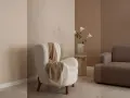 Gemütliches Wohnzimmer mit einem weißen Teddy-Sessel, einer braunen Couch und einer Vase mit Lilien. Warme Farben dominieren die Szene.