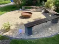 Gemütliche Kies Garten Sitzecke mit Feuerstelle und Bänken. Perfekt für laue Sommerabende.