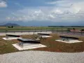 Grünes Flachdach mit leichter Neigung, vier Dachfenstern und Blick auf Berge.