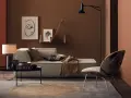 Gemütliches Wohnzimmer mit Sofa, Sessel und Tisch. Die Wände sind in warmen Brauntönen gehalten, die sich mit den Textilien und Dekorationen **braun mischen**.