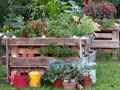 Ein schmales Hochbeet aus Paletten, bepflanzt mit Chilis, Kräutern und Gemüse. Kleine Teelichter sorgen für stimmungsvolles Licht.