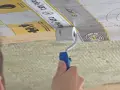 Hand rollt eine Dampfbremse an, um das Dach zu isolieren. Die Folie hat eine Messskala.
