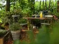 Gemütliche Gartenecke mit Tisch und Stühlen, umgeben von üppigem Grün. Rindenmulch garten ideen für eine natürliche Atmosphäre.