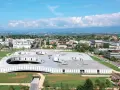 Das Rolex Learning Center in Lausanne, ein futuristisches Gebäude mit runden Öffnungen im Dach, umgeben von grünen Flächen und moderner Architektur.