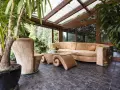 Gemütlicher Wintergarten mit bequemer Couch und Glascouchtisch. Pflanzen und viel Licht schaffen eine entspannte Atmosphäre, ideal zum Wintergarten einrichten.