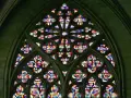 Ein farbenprächtiges Rosettenfenster im gotischen Baustil, das durch seine filigrane Steinarchitektur und das leuchtende Glas beeindruckt.