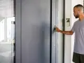 Mann mit Kopfhörern betätigt den Türöffner an der modernen zuwegung haus.