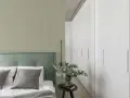 Ein Schlafzimmer mit einer Wand in hellem Olivgrün und einem Bett mit grünem Kopfteil. Der Unterschied zwischen Khaki und Oliv ist hier subtil, aber präsent.