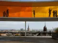 Silhouetten von Menschen auf dem Regenbogenpanorama des Kunstmuseums Aarhus. Blick auf die Stadt und das Meer.