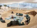 Helle, offene Bibliothek in Oodi Helsinki mit Menschen, die lesen und sich entspannen. Holzmöbel und große Fenster schaffen eine einladende Atmosphäre.