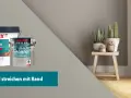 Zwei Eimer Wandfarbe, ein großer weißer und ein kleinerer mit "Farbakzente" Motiv. Daneben ein Hocker mit Pflanzen. Text: "Wand streichen mit Rand".