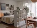 Gemütliche 1 Zimmer Wohnung einrichten 30qm: Bett, Regal als Raumteiler, Esstisch mit Stühlen und Pflanzen.