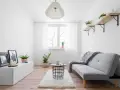 Ein gemütliches Schlauchzimmer einrichten: Helles Sofa, Teppich, Beistelltisch, Pflanzen und Bilder schaffen eine wohnliche Atmosphäre.
