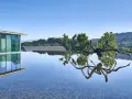 Skulptur einer Spinne spiegelt sich im Wasser vor dem modernen Gebäude des Chateau La Coste.