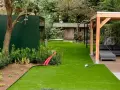 Moderne Gartenaufteilung mit Kunstrasen, Holzpavillon, Lounge-Möbeln und grüner Wand. Tolle Ideen für Ihren Garten!