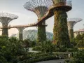 Futuristische Supertrees und Gewächshäuser in den Gardens by the Bay, Singapur, mit Menschen, die auf Wegen spazieren.