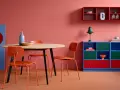 Ein Esszimmer mit roten Akzenten: Orange Stühle, ein blauer Schrank und rote Regale zeigen, welche Farben passen zu Rot.