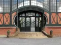 Eingang im artdeco stil mit Ziegelmauerwerk, geschwungenen Metallverzierungen und einem beeindruckenden Buntglasfenster.