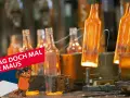 Glühende Glasflaschen in einer Fabrik. Die Maus fragt sich, wann wurde Glas erfunden?