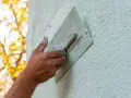 Hand bearbeitet eine Fassade mit einer Kelle. Verschiedene Putztechniken fassade werden hier angewendet, um eine rustikale Textur zu erzeugen.