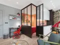Clever 35 qm wohnung einrichten: Schlafbereich, Küche und Arbeitsplatz sind durch Glaswände getrennt. Bunte Akzente wie der rote Stuhl und die Tapete beleben den Raum.