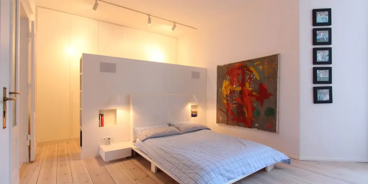 Modernes Schlafzimmer mit Bett, Kunstwerk und Einbauschränken. Tolle Renovierungsideen für minimalistische Räume.
