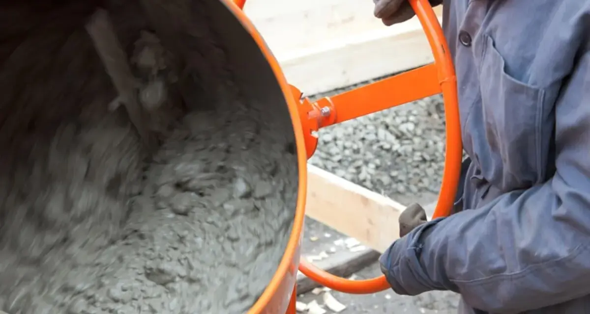 Eine Betonmischmaschine rührt den feuchten Mörtel, der zeigt, aus was Beton besteht: Zement, Wasser und Zuschlagstoffe.
