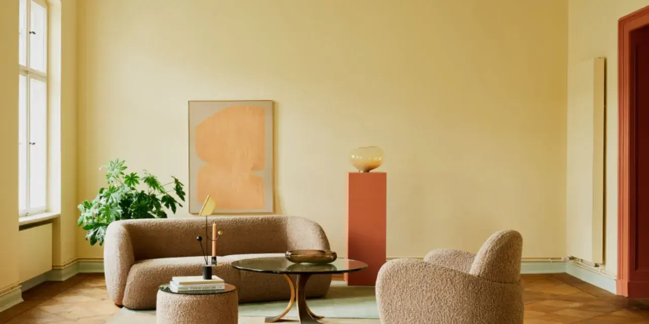 Ein Wohnzimmer mit gelben Wänden und einer grünen Decke, die frisch gestrichen wurde. Gemütliche Bouclé-Möbel und ein runder Couchtisch laden zum Verweilen ein.