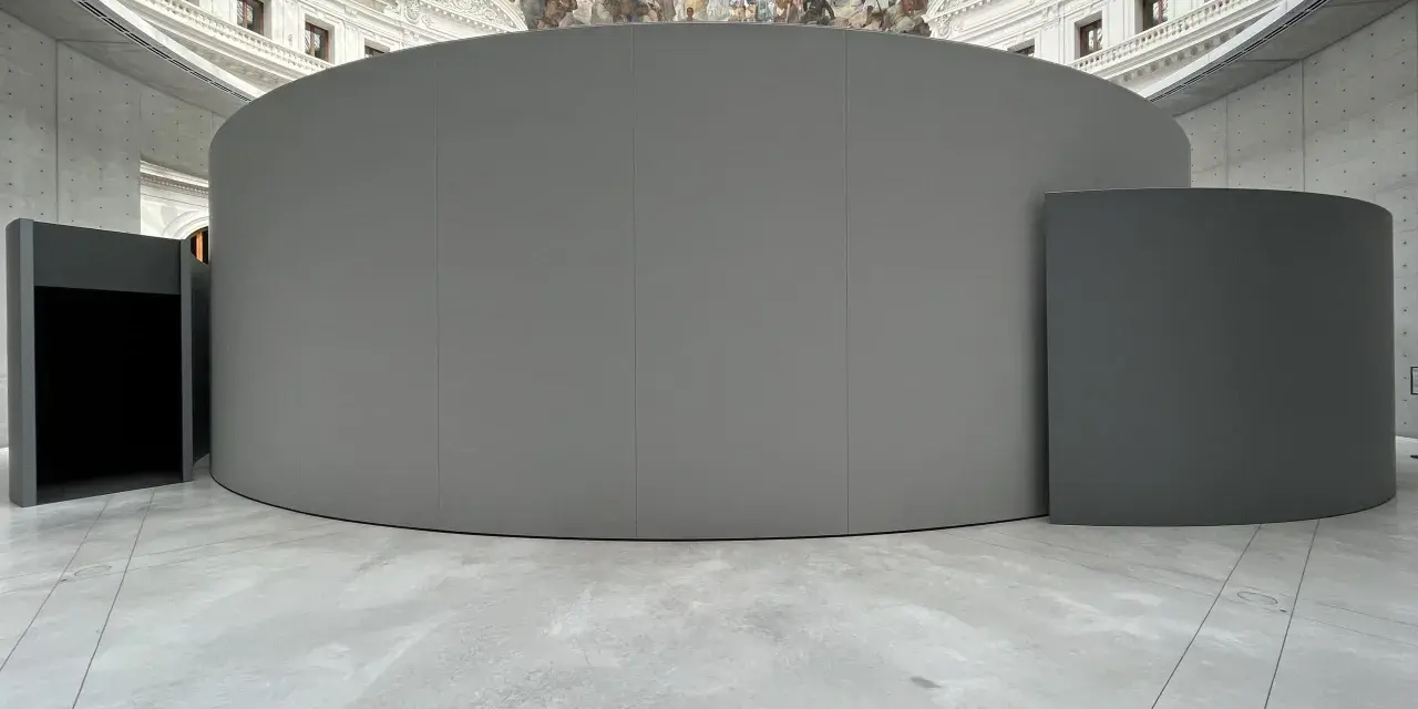 Graue, runde Installationen im Inneren eines Gebäudes mit einer Deckenmalerei, die an eine historische **Bourse de commerce** erinnert.