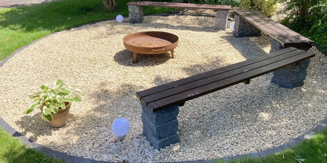 Gemütliche Kies Garten Sitzecke mit Feuerstelle und Bänken. Perfekt für laue Sommerabende.