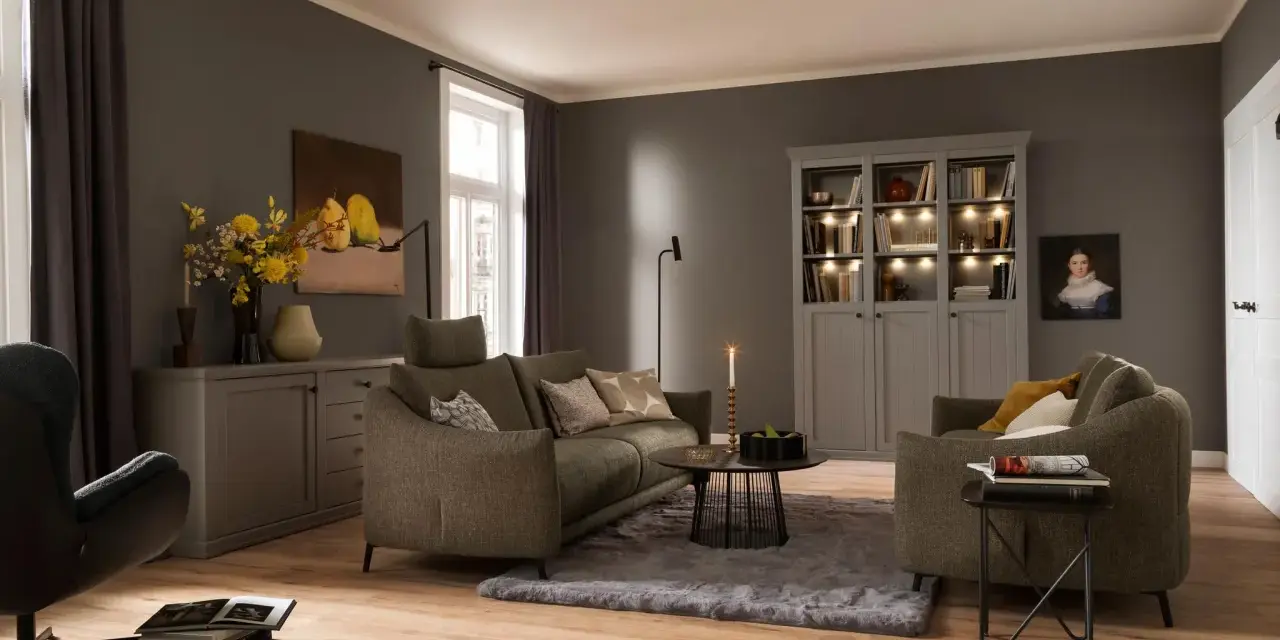 Gemütliches Wohnzimmer mit einem weichen, grauen Teppich unter dem Sofa und einem Sessel.