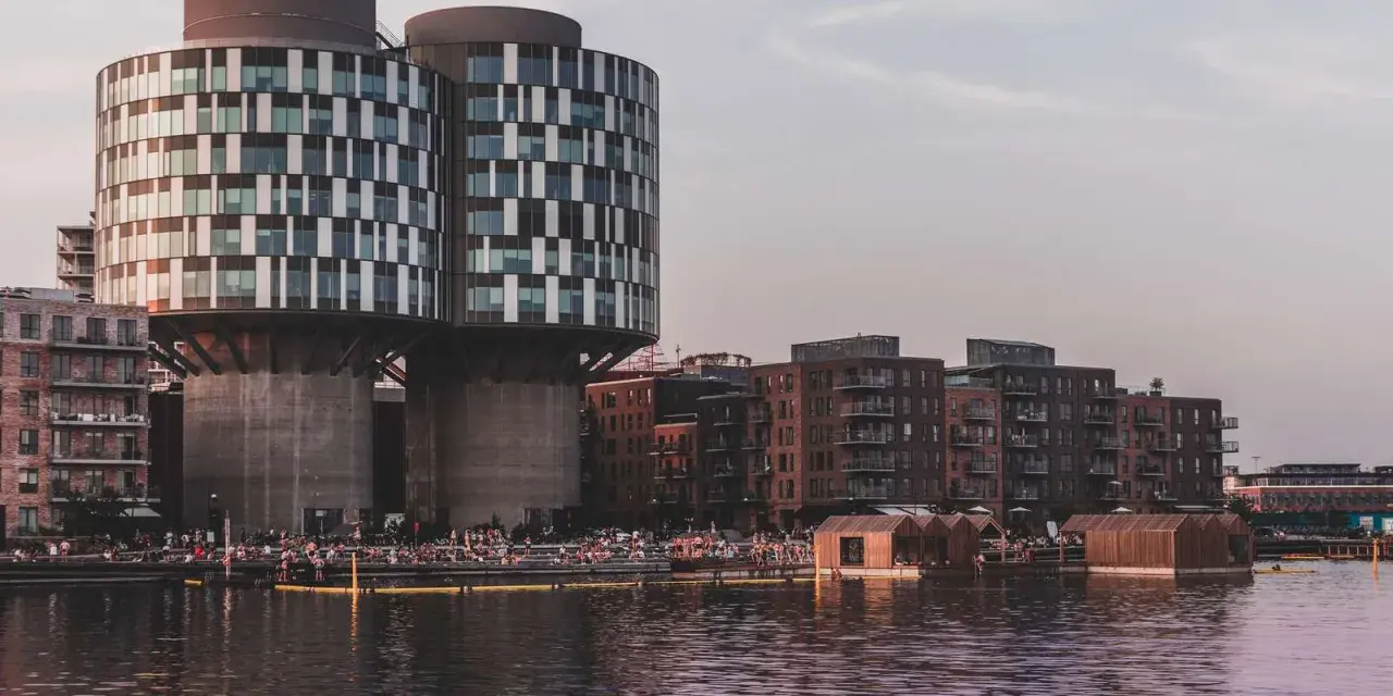 Moderne Architektur und schwimmende Holzhäuser am Wasser in Nordhavn Kopenhagen. Menschen genießen die Abendsonne.