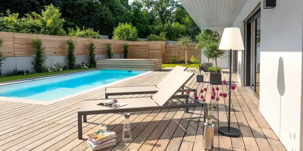 Traumhafte gartengestaltung mit pool und terrasse. Zwei Liegen laden zum Entspannen ein, während der Pool erfrischt.