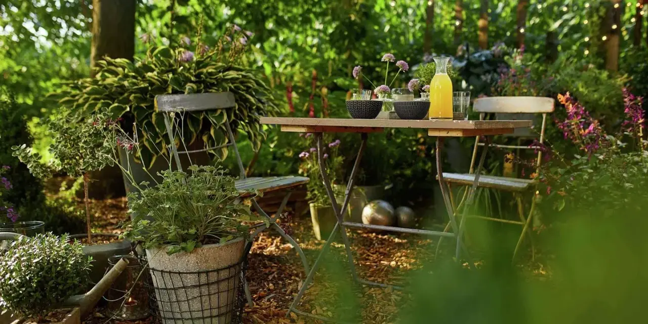 Gemütliche Gartenecke mit Tisch und Stühlen, umgeben von üppigem Grün. Rindenmulch garten ideen für eine natürliche Atmosphäre.