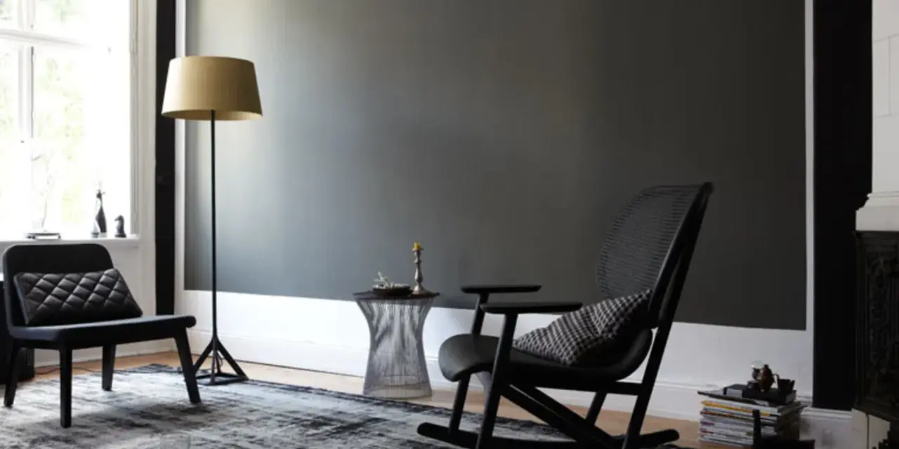 Stilvolles Wohnzimmer mit dunkler wand schwarz streichen Idee. Schwarzer Schaukelstuhl, Sessel, Stehlampe und Teppich.