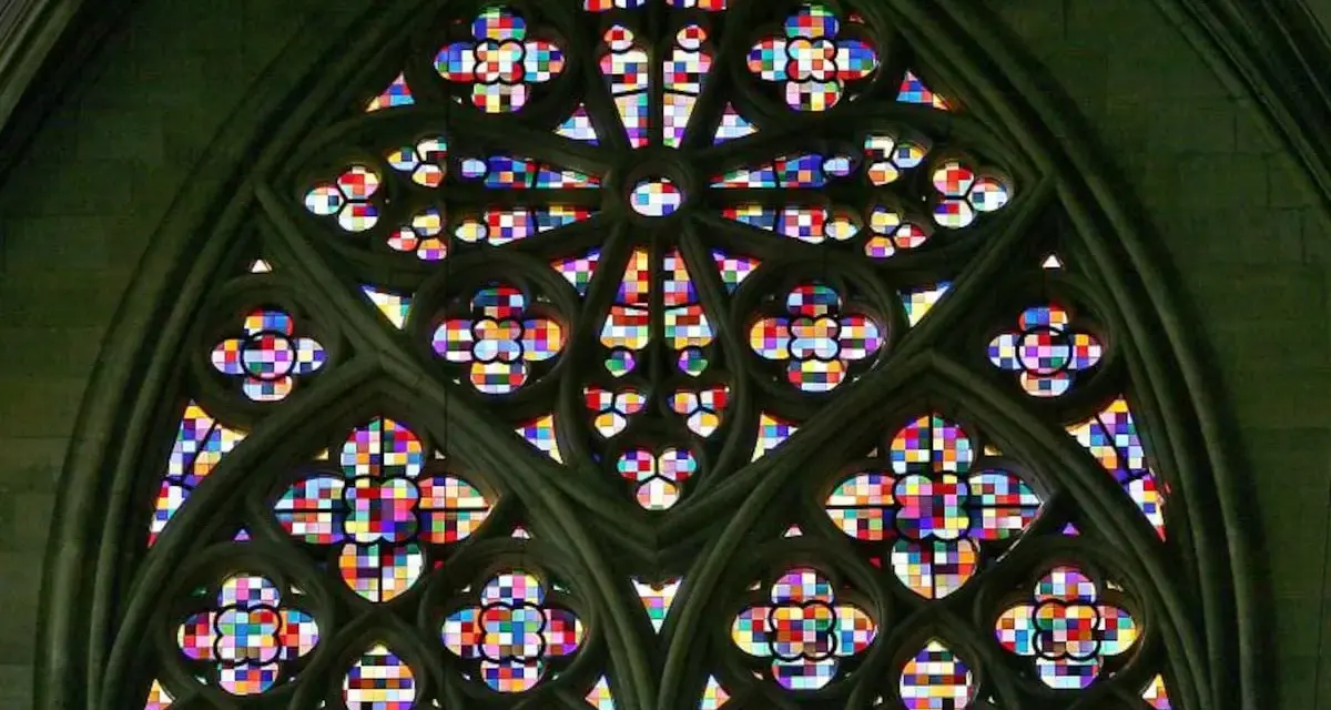 Ein farbenprächtiges Rosettenfenster im gotischen Baustil, das durch seine filigrane Steinarchitektur und das leuchtende Glas beeindruckt.