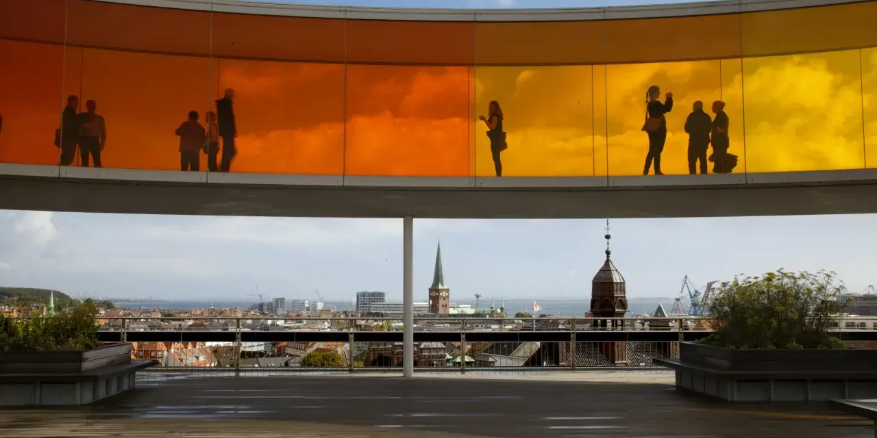 Silhouetten von Menschen auf dem Regenbogenpanorama des Kunstmuseums Aarhus. Blick auf die Stadt und das Meer.