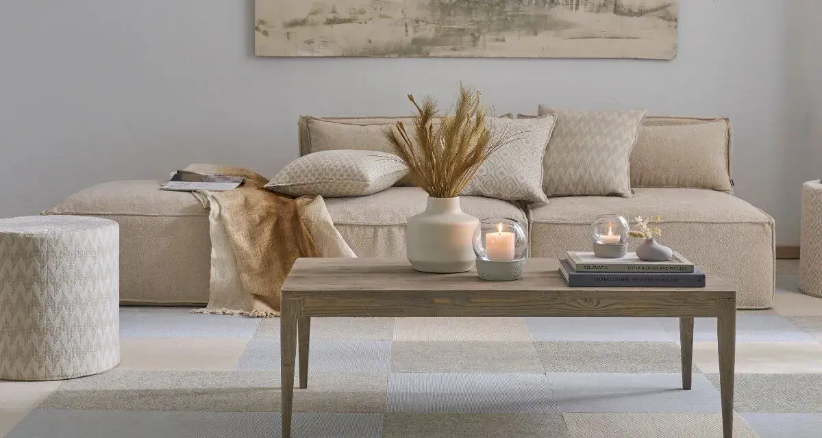 Gemütliches, **ästhetisches Zimmer** mit beigem Sofa, Holztisch, Kerzen und Deko.