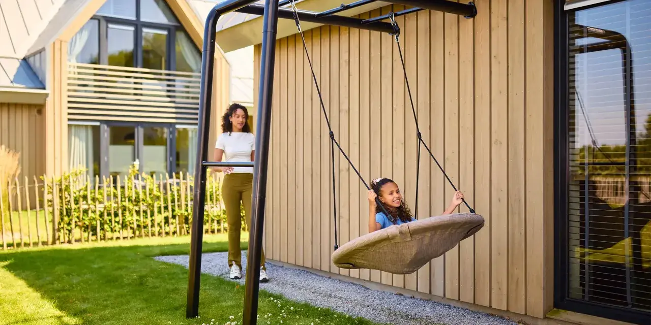 Tolle spielecke garten ideen kinder: Ein Mädchen schaukelt fröhlich, während eine Frau zusieht.
