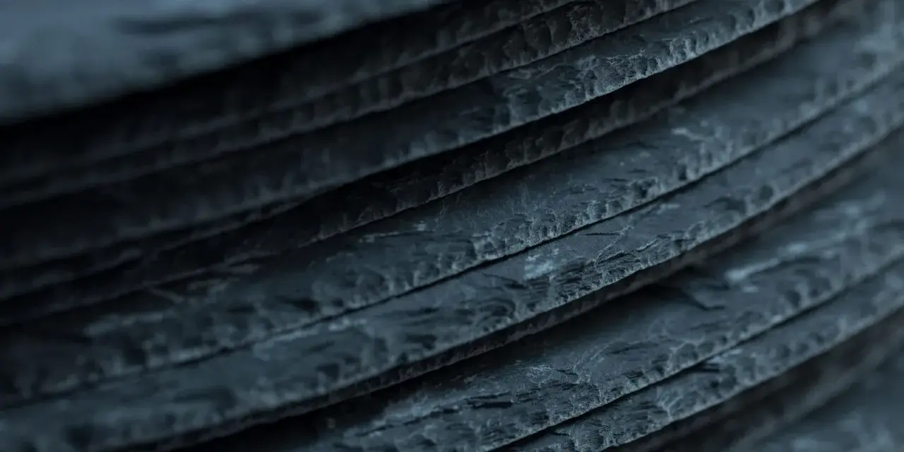 Stapel von dunklen Schieferplatten, die eine interessante Textur aufweisen. Es ist ein weit verbreiteter Irrtum, dass Schiefer giftig ist.