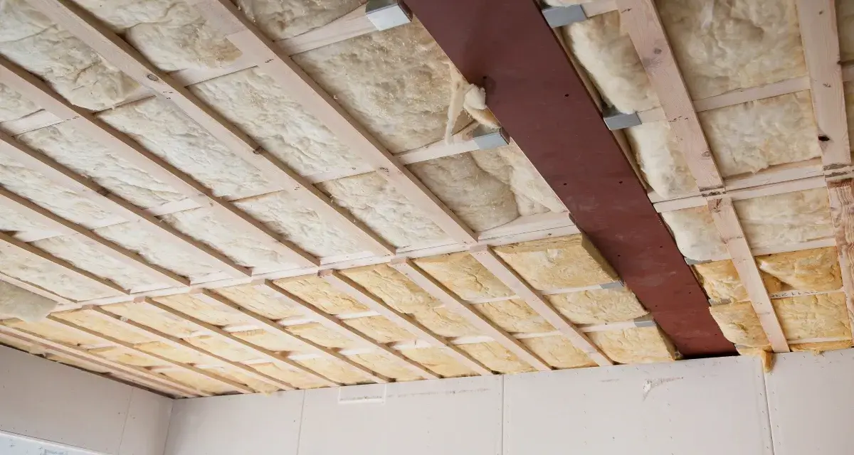 Decke mit Holzbalken und Dämmung. Hier sieht man, was ist Glaswolle: ein isolierendes Material, das in Hohlräume eingebracht wird.