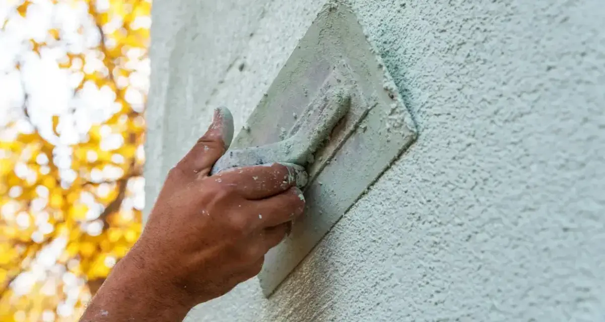 Hand bearbeitet eine Fassade mit einer Kelle. Verschiedene Putztechniken fassade werden hier angewendet, um eine rustikale Textur zu erzeugen.
