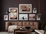 Braune und beige Töne passen wunderbar zu Schwarz. Ein stilvolles Wohnzimmer mit brauner Ledercouch, Kunstwerken und einem Couchtisch.