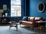 Ein Wohnzimmer mit braunem Ledersofa und blauen Wänden. Das Braun ist die perfekte gegenfarbe von braun, die dem Raum Tiefe verleiht.