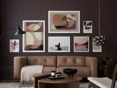 Braune und beige Töne passen wunderbar zu Schwarz. Ein stilvolles Wohnzimmer mit brauner Ledercouch, Kunstwerken und einem Couchtisch.
