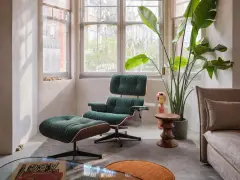 Gemütliches mid century wohnzimmer mit einem dunkelgrünen Sessel und Hocker, einer großen Zimmerpflanze und einem beigefarbenen Sofa.